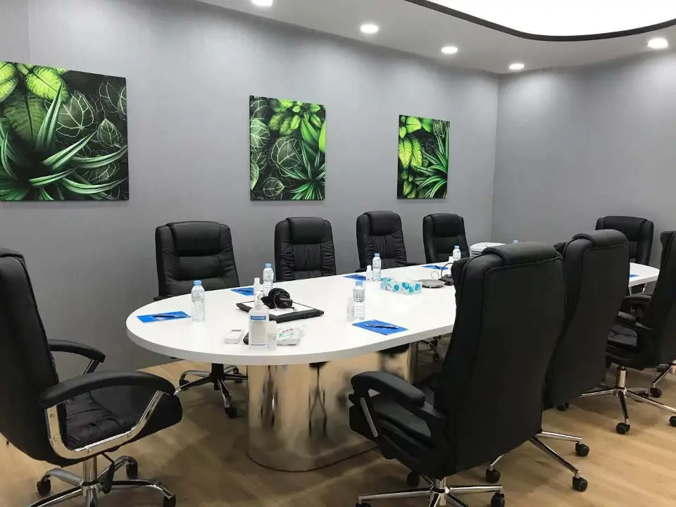 Meeting room with round table, black chairs and leaf artwork on grey walls