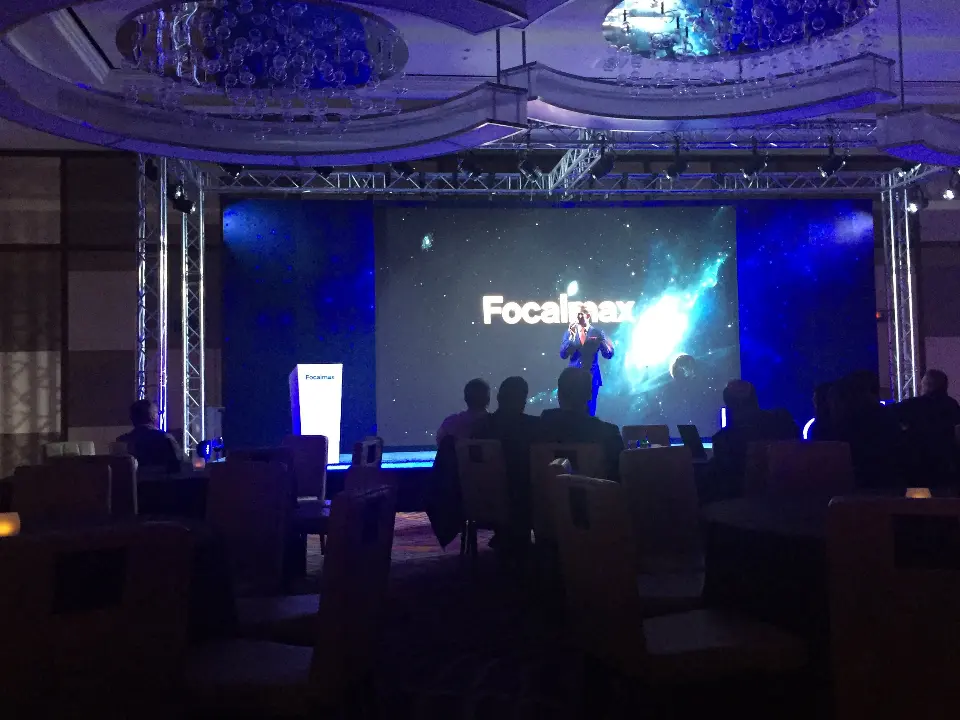 Audience facing the stage as the Focalmax logo appears on the screen