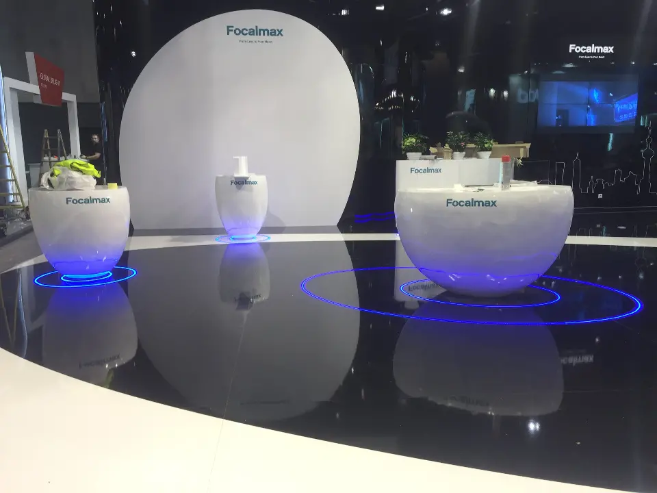 Glossy black floor reflecting white pods and a tall white oval backdrop