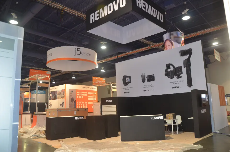 During build-up: REMOVU hanging sign over grey graphic walls and low black counters