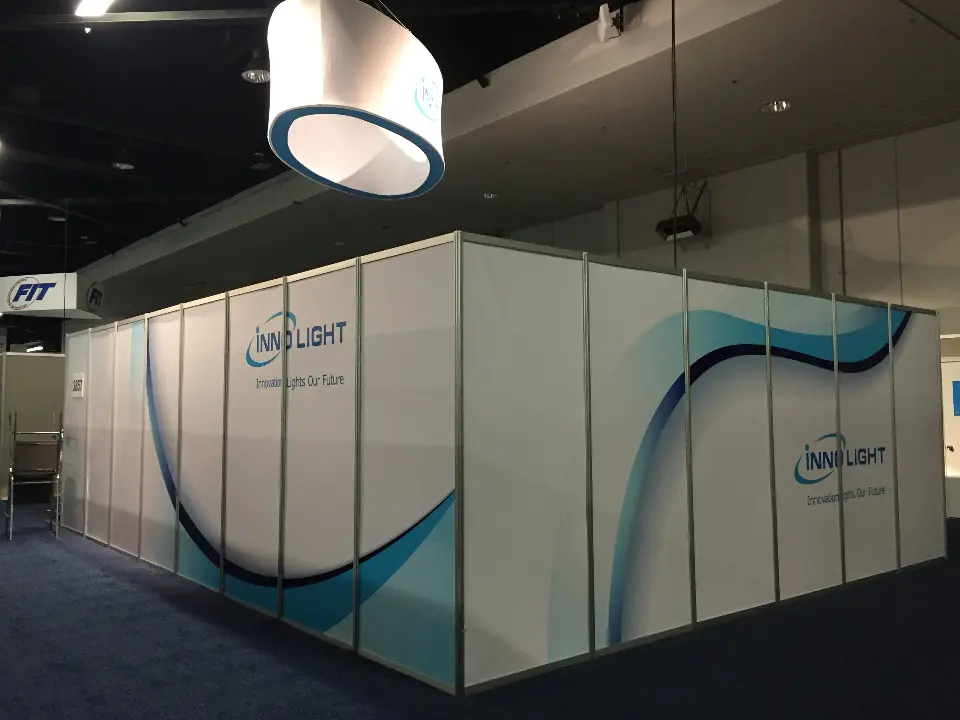 Corner of the enclosed booth showing blue waves and the INNOLIGHT logo on white panels