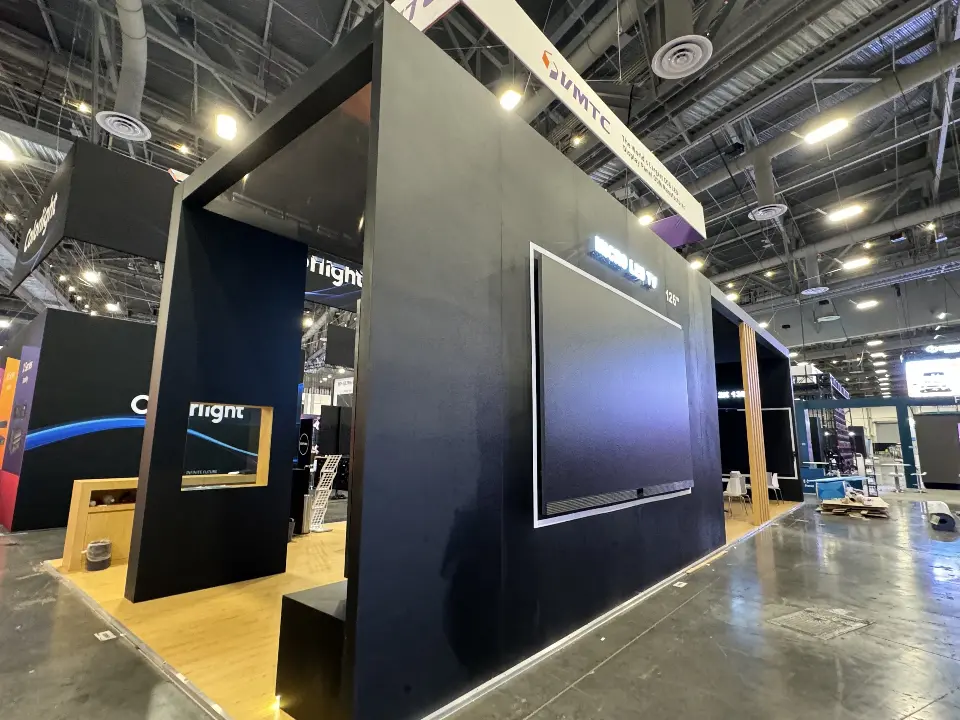 Black Colorlight booth frame with wood-look bench and wall-mounted screen inside