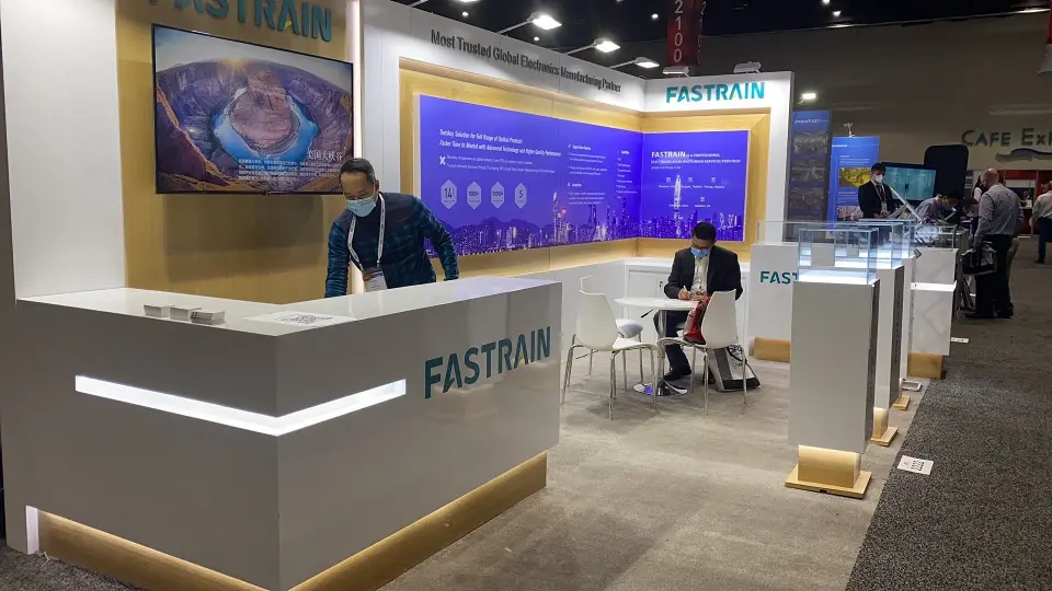 Staff working at the FASTRAIN counter with screen and graphic wall behind