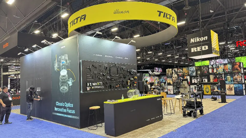 Black Tilta wall with a pegboard of camera accessories, an optics graphic and a yellow-topped counter