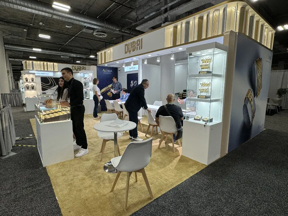 Jewelry stand with glass showcases, white tables and visitors at work