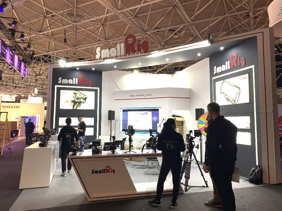Front angle of the SmallRig booth with logo counter, back-wall screen and visitors