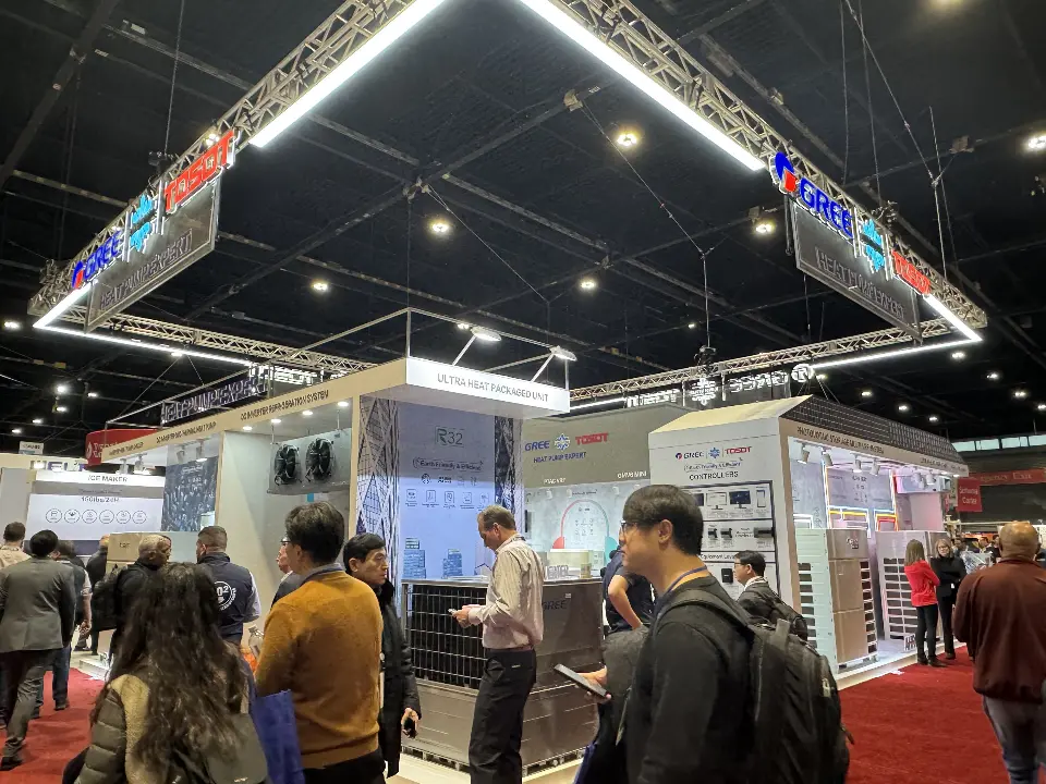 Wide show-day view of the whole GREE booth under the lit triangular truss