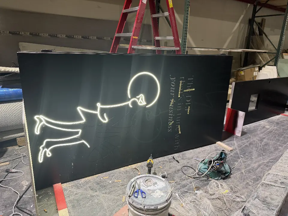 Glowing white line-art figure on a black Jazz wall panel during booth installation