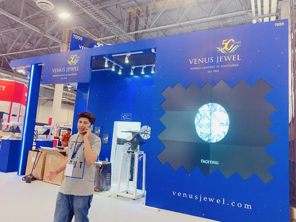 Diamond graphic on blue wall above white display stands and venusjewel.com lettering