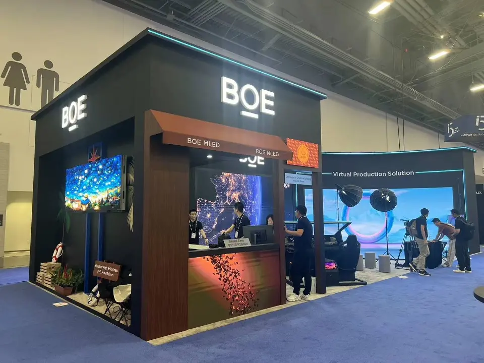 Front corner on blue carpet with a lit screen, demo area and soft lights