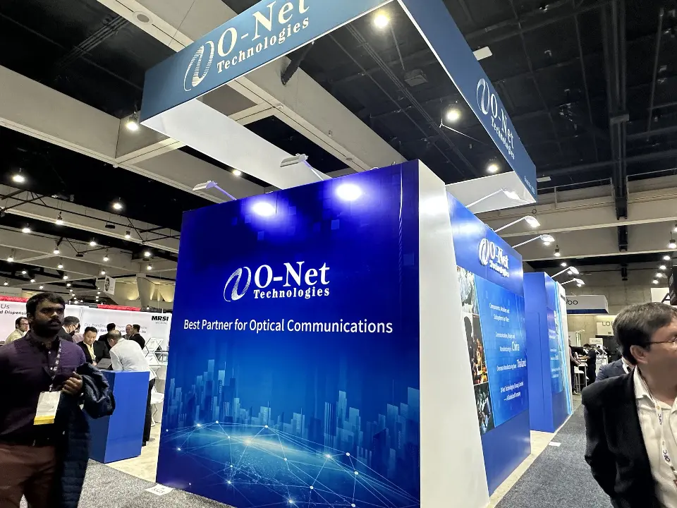 Navy tower graphic reading Best Partner for Optical Communications with visitors nearby