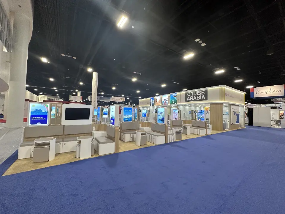 Long side of the pavilion with white counters and backlit graphics on blue carpet