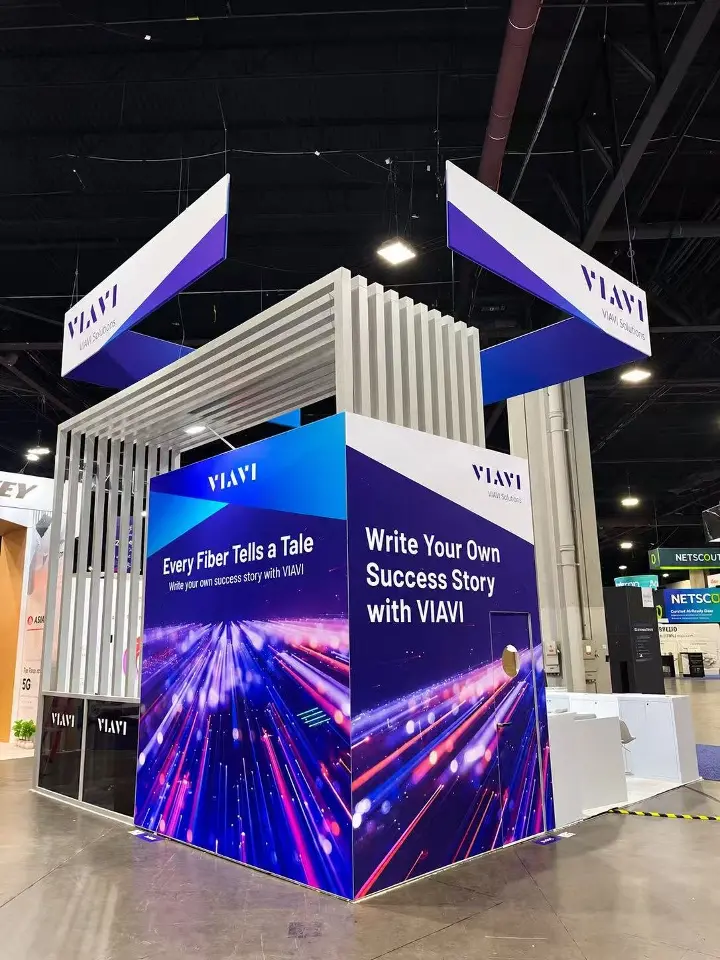Corner tower of the VIAVI booth printed with Every Fiber Tells a Tale under two hanging VIAVI banners