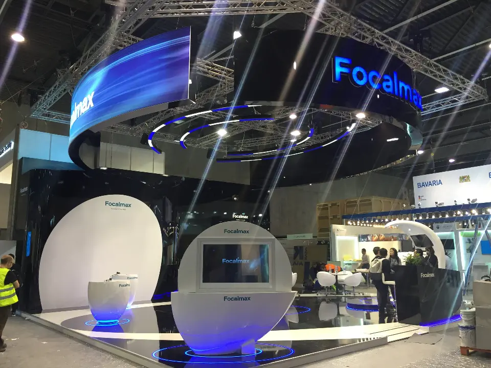 Show-day view of visitors around white pods under the blue-lit ring header