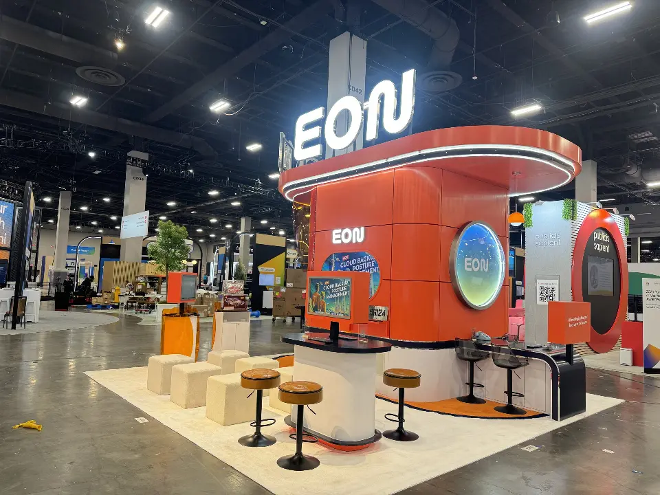EON booth with wood-look stools and white cubes around the tower