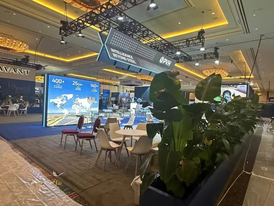 During build-up: tall plants in blue planters screening the PVH lounge and backlit graphics
