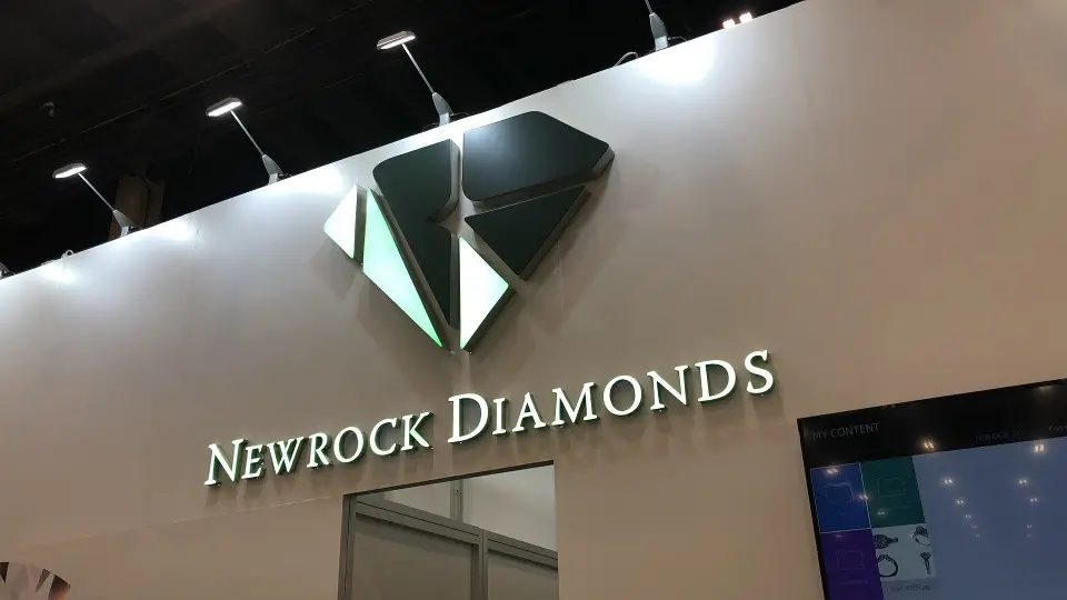 Close view of the lit Newrock Diamonds sign and green diamond logo above the entrance