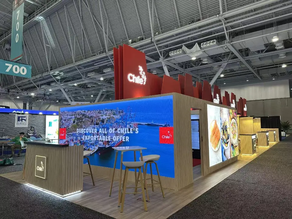 Chile pavilion corner with large video screen, wood-slat walls and red angled header panels