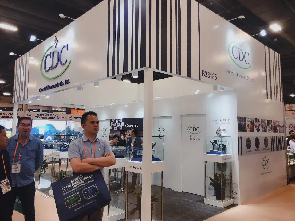 Open CDC booth with visitors, stripe header, logos and glass showcases with plants