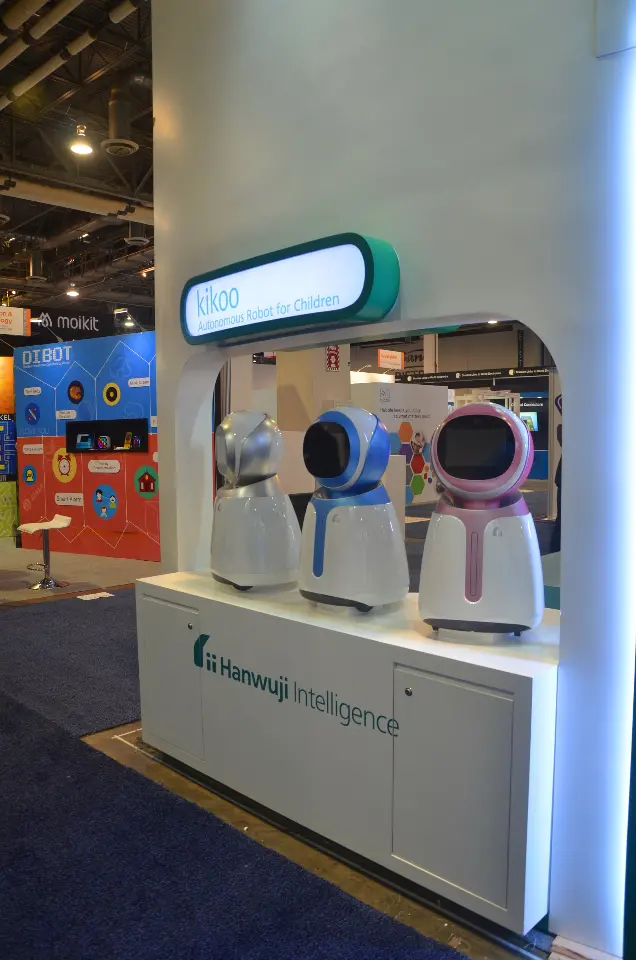White display counter with small robots under a teal-framed screen