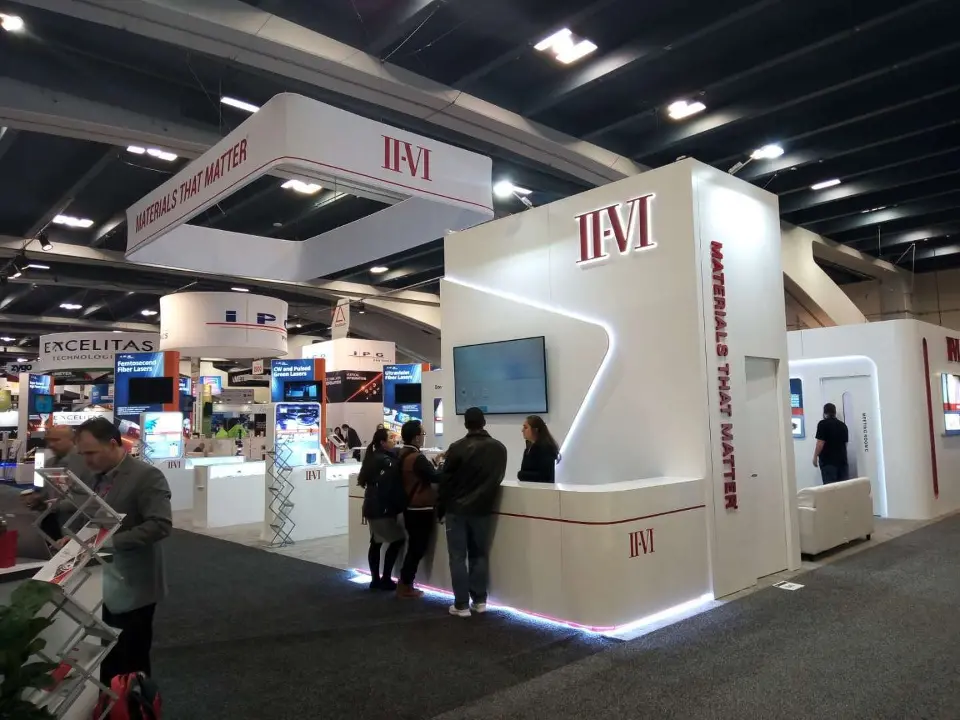 Visitors at the front of the booth under the tower with curved light strip
