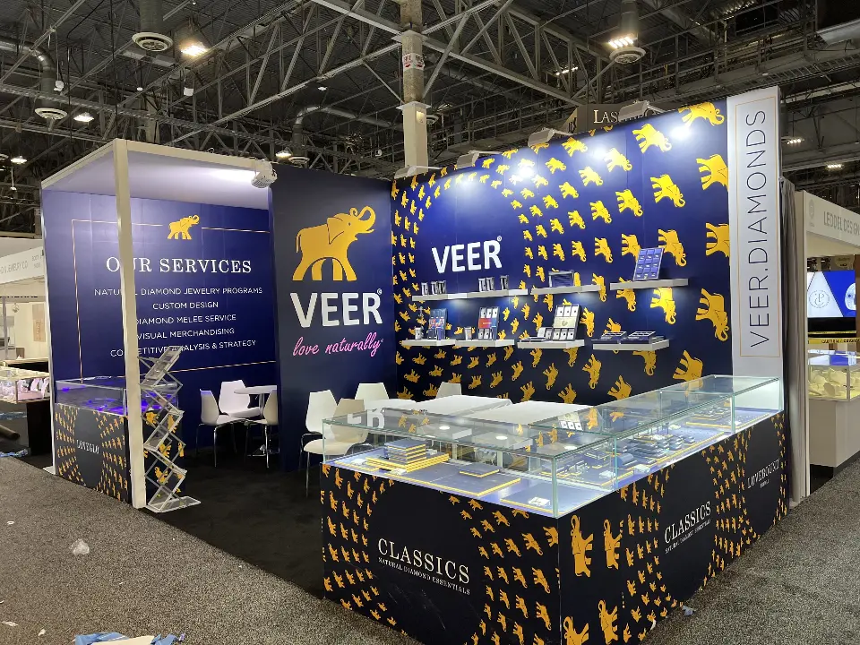 VEER booth corner with gold elephant pattern wall, lit floating shelves and Classics glass showcases