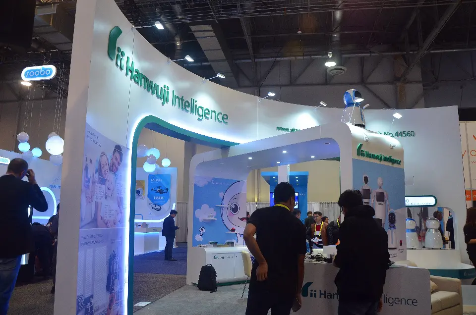Curved white wall with green Hanwuji Intelligence lettering above a teal-lit arched portal into the booth